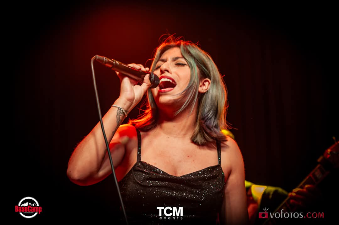 Female vocalist singing passionately against a red backdrop