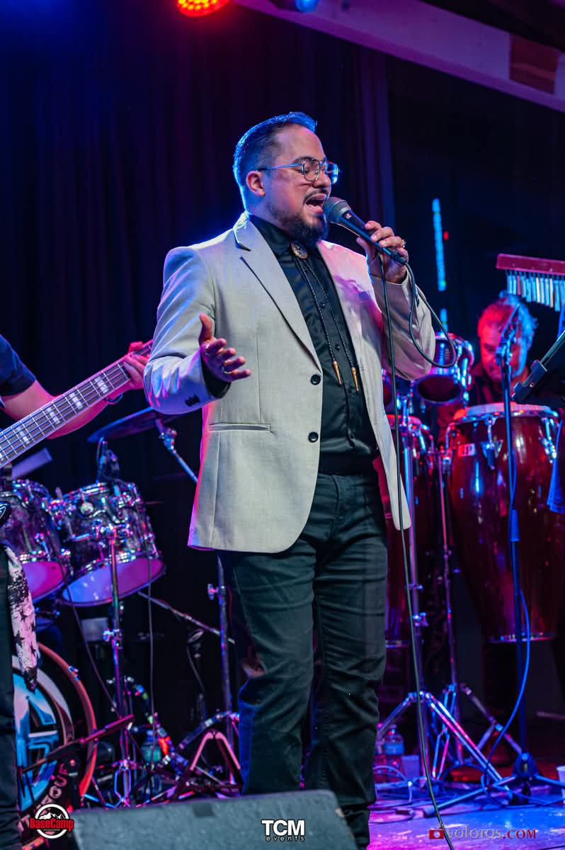 Lead vocalist performing with the drummer and percussion behind him
